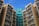 High-rise residential buildings with numerous windows and air conditioning units attached, displaying a combination of beige and teal colors under a clear blue sky.