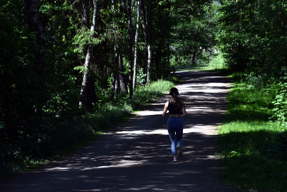 A woman running between green trees