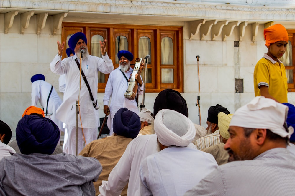 man speaking on microphone in front of group of people