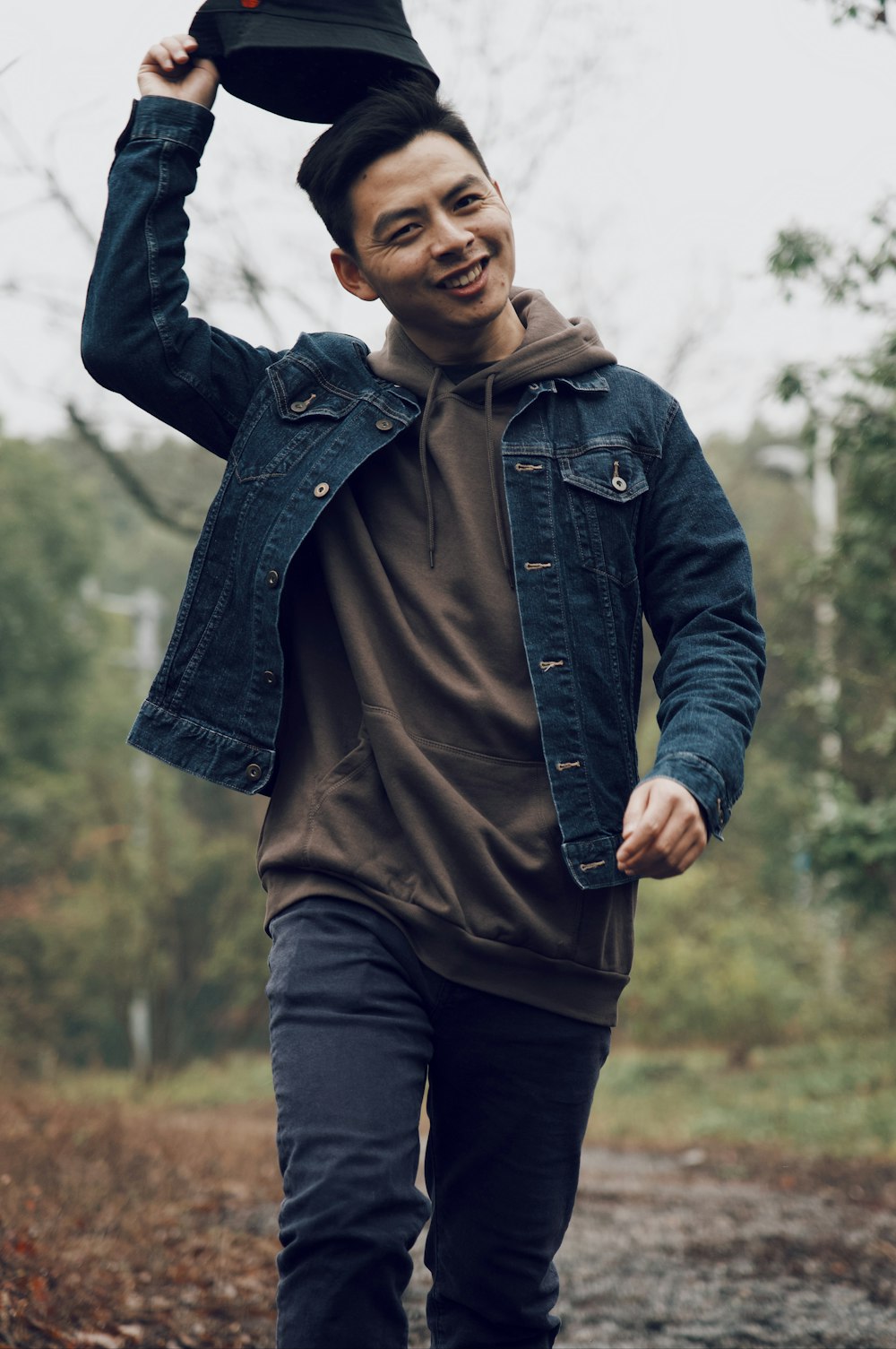 smiling man wearing denim jacket holding hat