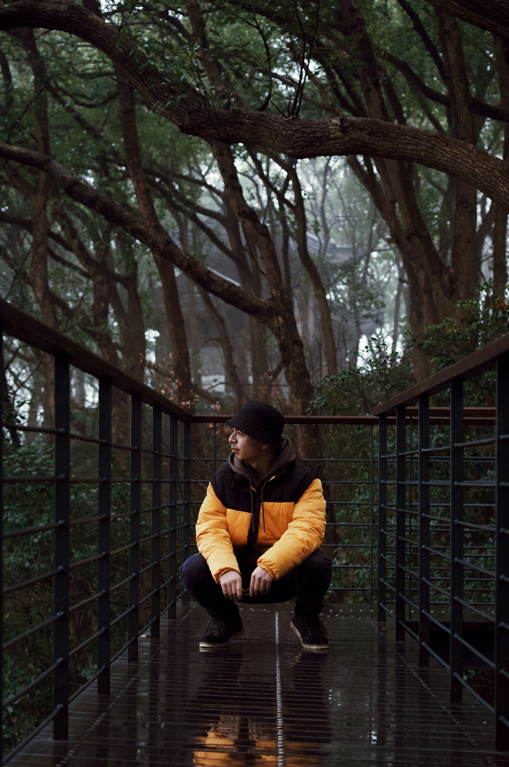 검은 색과 노란색 재킷을 입은 남자가 나무 근처에 앉아 있습니다.