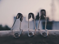 A row of shiny hook pins lined up neatly on a metal surface, catching the light.