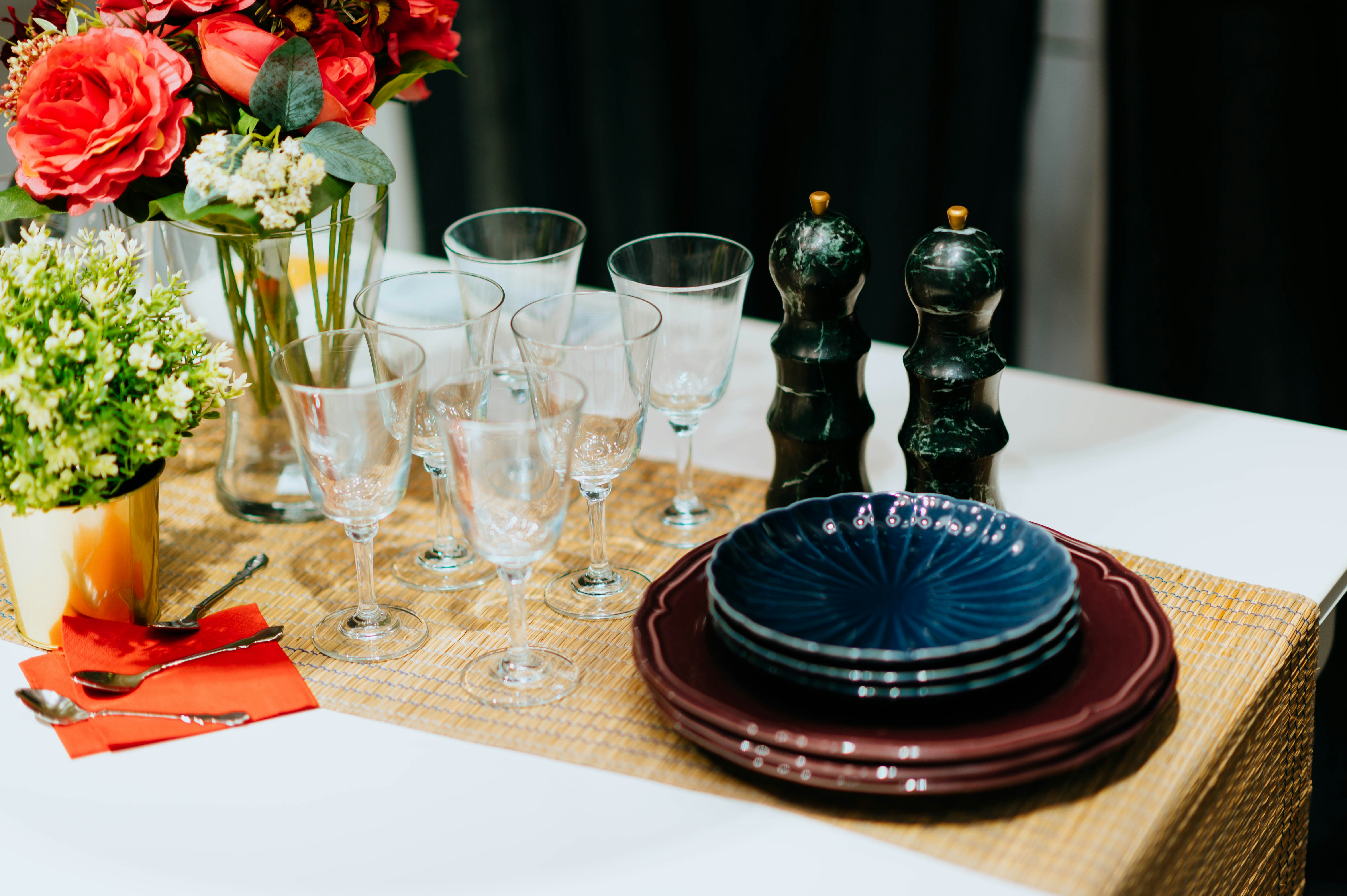 Dining table set with glasses, decorative plates, and floral centerpieces.
