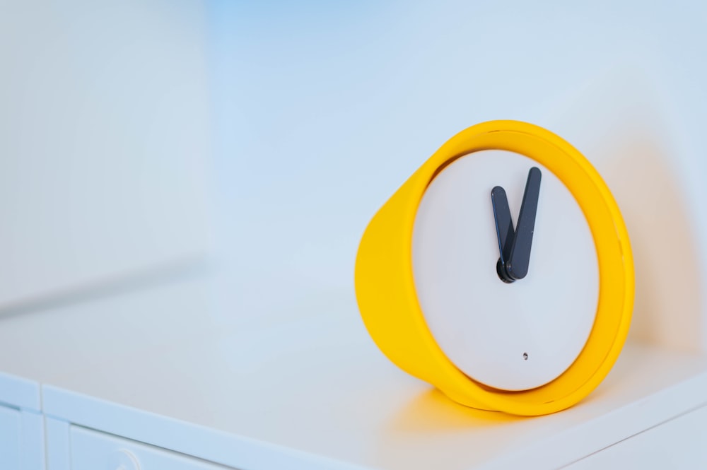 round white and yellow analog desk clock displaying 12:05
