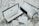 An elegant pen encased in a black and white box is opened to reveal its contents. Next to the box sits an accompanying blue and white outer packaging featuring drawings. A card with hand-written notes lies nearby on a textured surface, adding a personalized touch.
