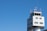 A modern air traffic control tower with a sleek design and several antennas on top set against a clear blue sky.