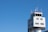 A modern air traffic control tower with a sleek design and several antennas on top set against a clear blue sky.