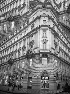A tall, ornate European building with intricate architectural details and multiple windows. The lower portion features a CSOB bank entrance. The building exhibits classical styling with arched windows and decorative elements.