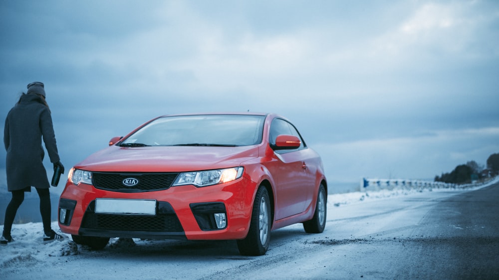 person standing beside Kia coupe, car types, mid size compact