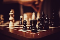 A close-up of hands playing chess on a wooden board.