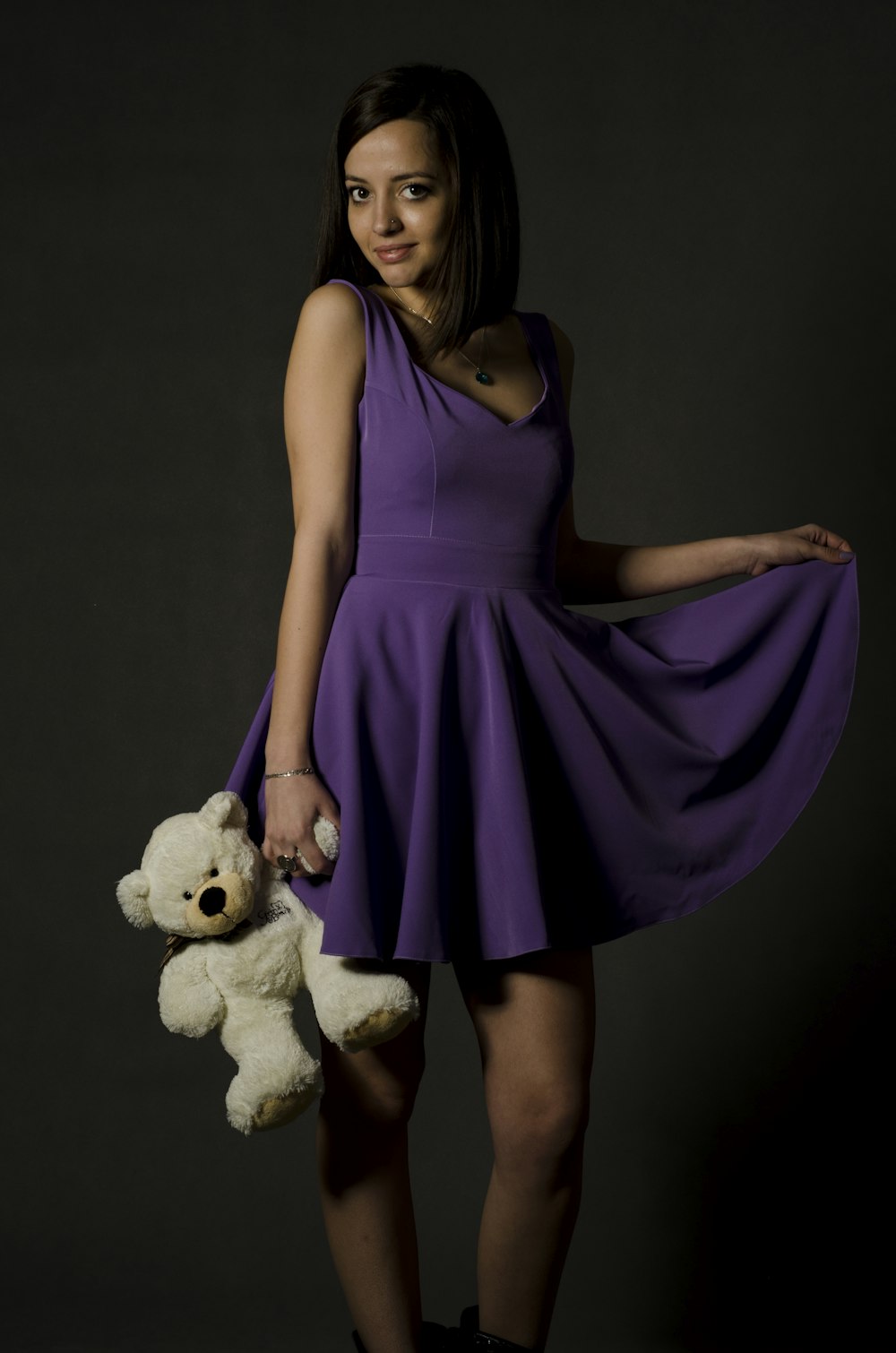 woman in purple sleeveless dress holing white teddy bear