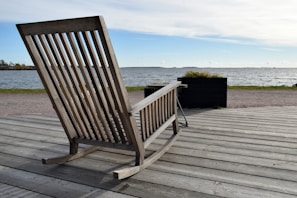 A handcrafted wooden rocking chair designed for kids, placed on a wooden deck.