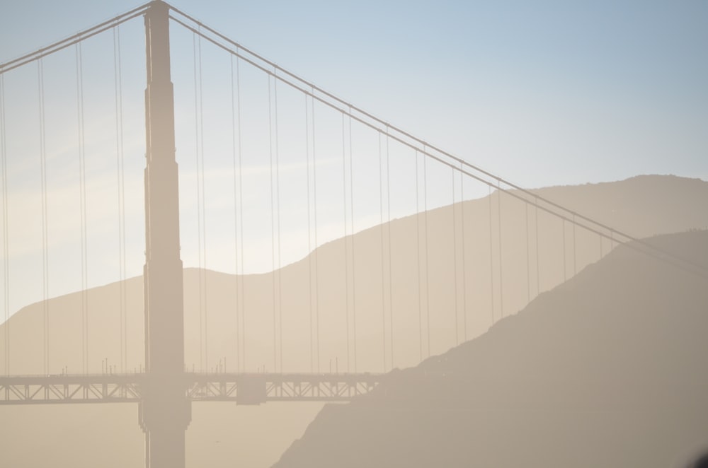 suspension bridge near mountain silhouette illustration