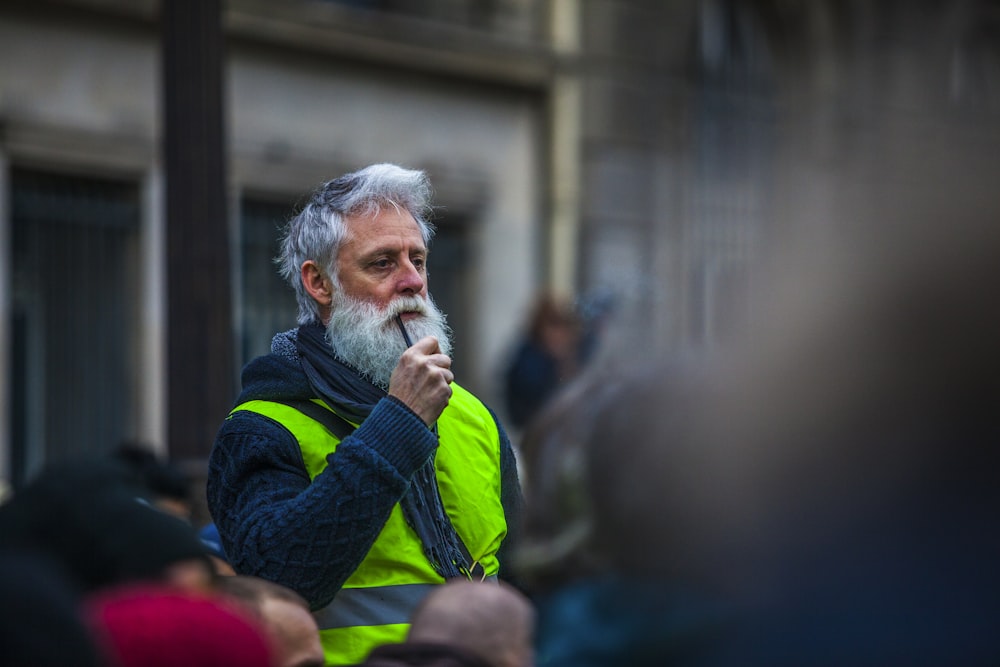 selective focus photography of man wearing blue cable knit jacket and green reflective vest