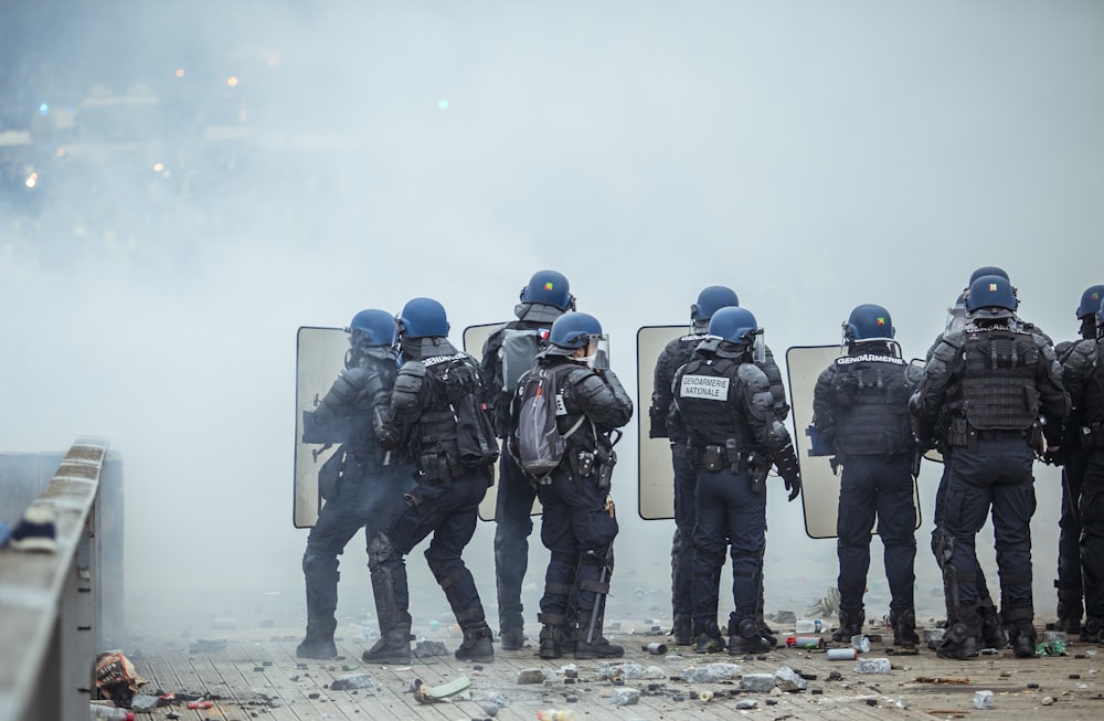riot police holding shield in front of smoke