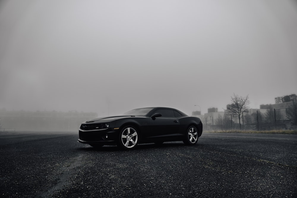 Dodge Challenger noire sur la route par temps de brouillard