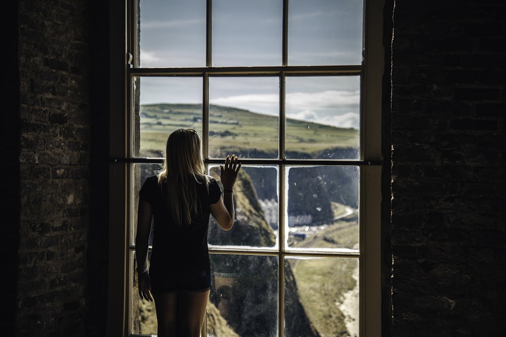 donna che guarda fuori dalla finestra di vetro