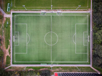 Outdoor sports field with students playing soccer on a green, well-maintained grass pitch