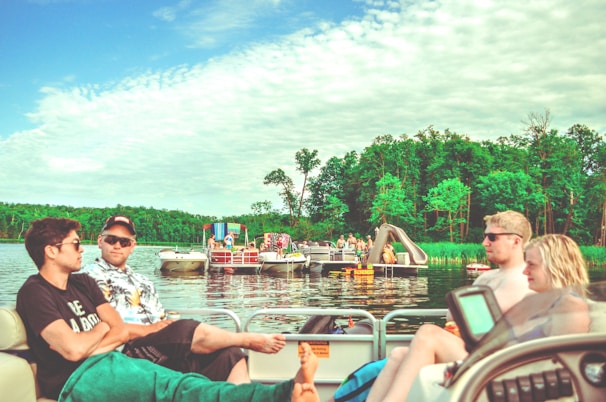 A group of friends laughing together on a boat ride across a serene lake.
