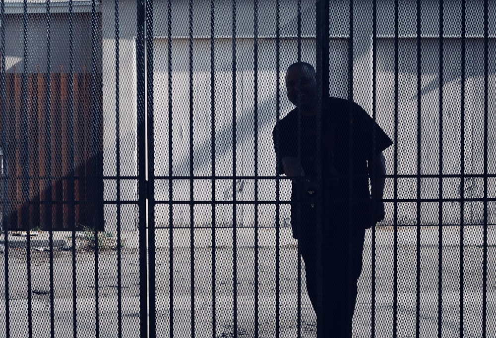 man trying to open metal gate during daytime