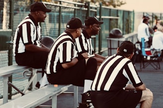 four man wearing black and white stripe shirts sitting on chairs