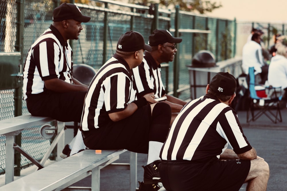 four man wearing black and white stripe shirts sitting on chairs