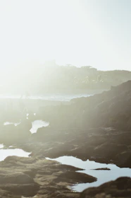 Soft, diffused light illuminating a rocky beach at dusk, highlighting textures and the calm after the storm.