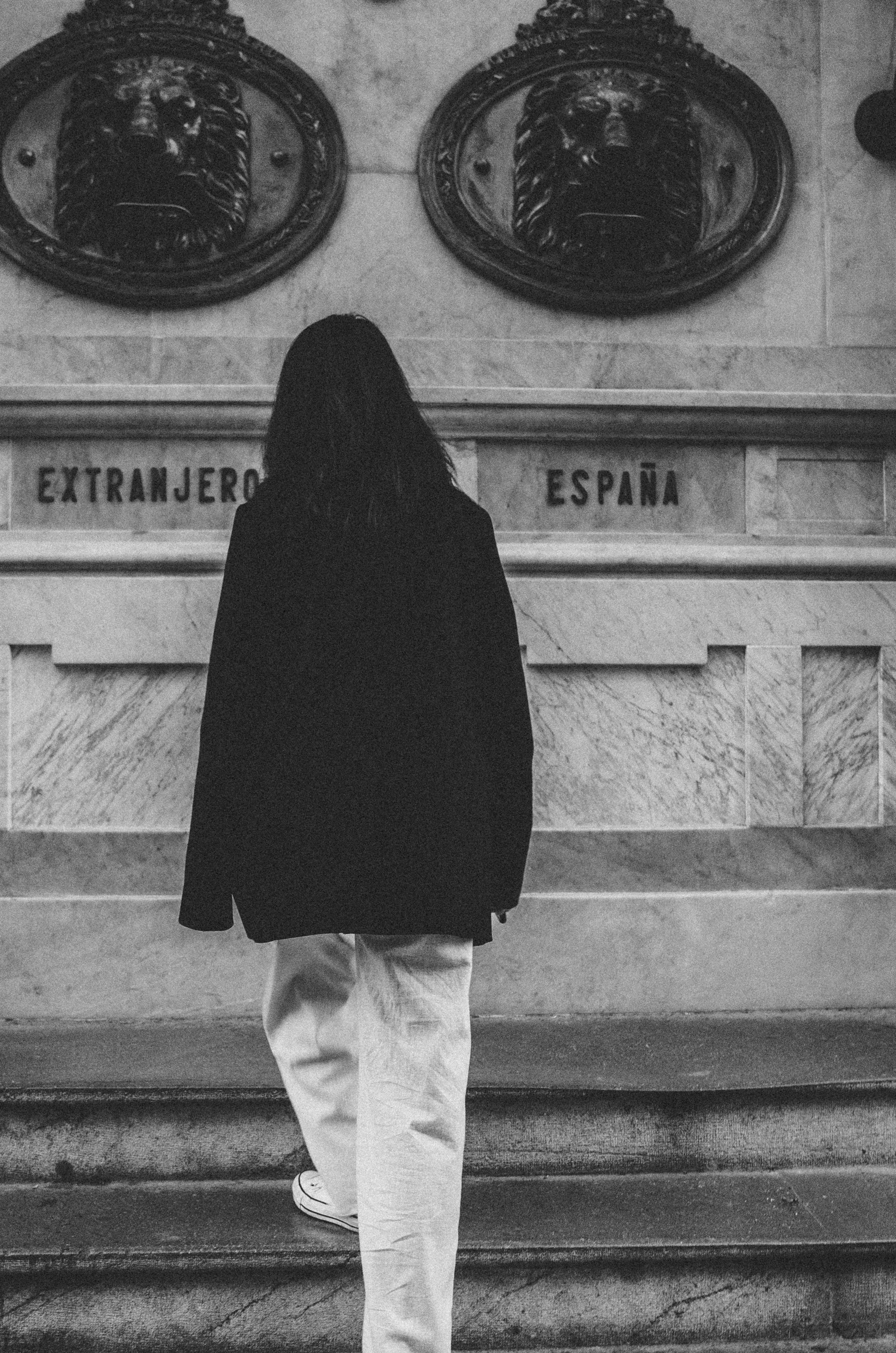 grayscale photo of person in jacket walking on stairs