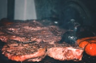 Close-up of juicy grilled meat sizzling on the barbecue with smoke rising.