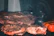 Close-up of a juicy ribeye steak sizzling on a grill with herbs and spices around.