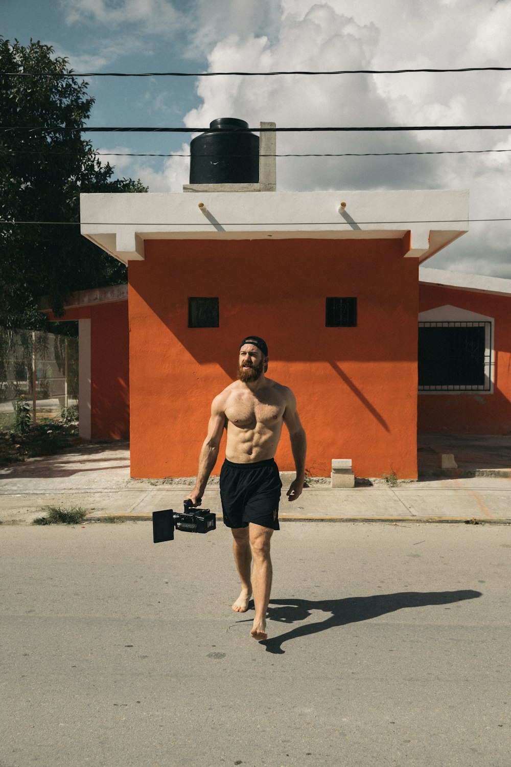 topless man wearing black shorts crossing street during daytime