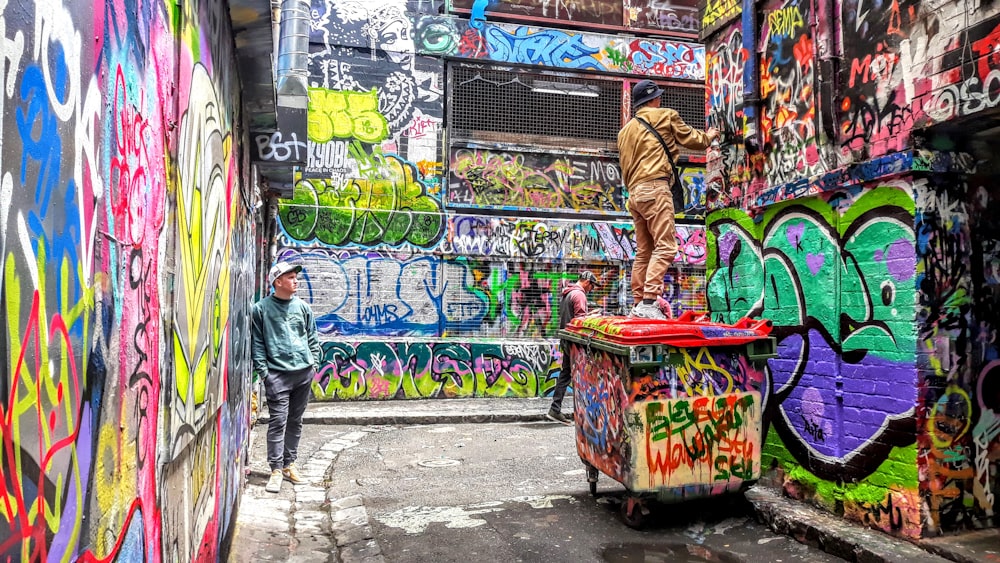 two men surrounded by buildings covered with graffiti