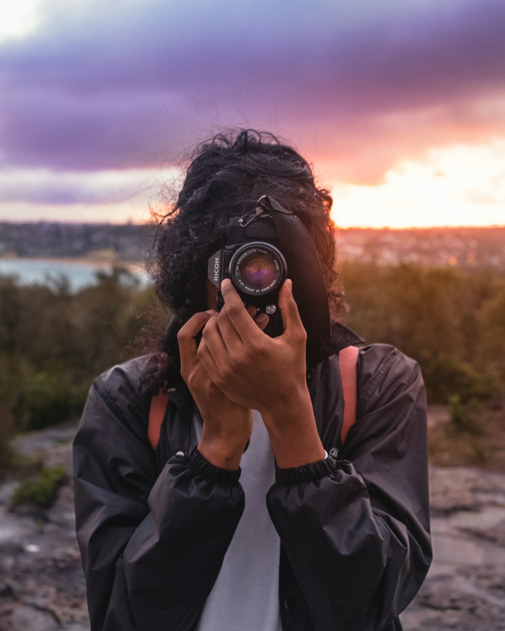 person wearing black jacket taking picture using DSLR camera