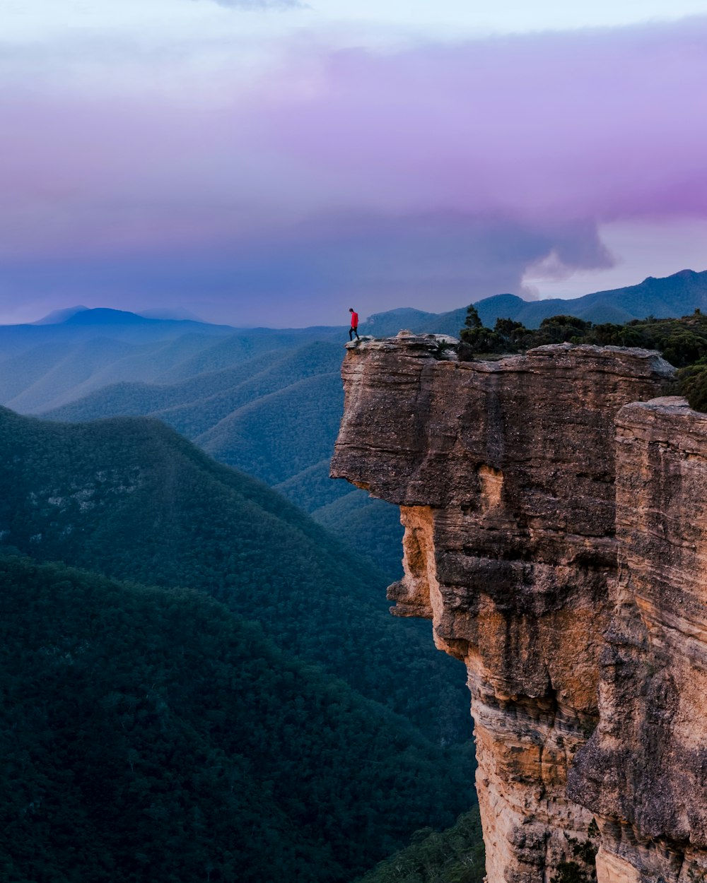 person standing on the edge of a cliff during daytime