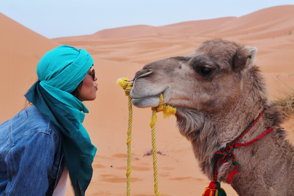 woman wearing blue jacket facing brown camel