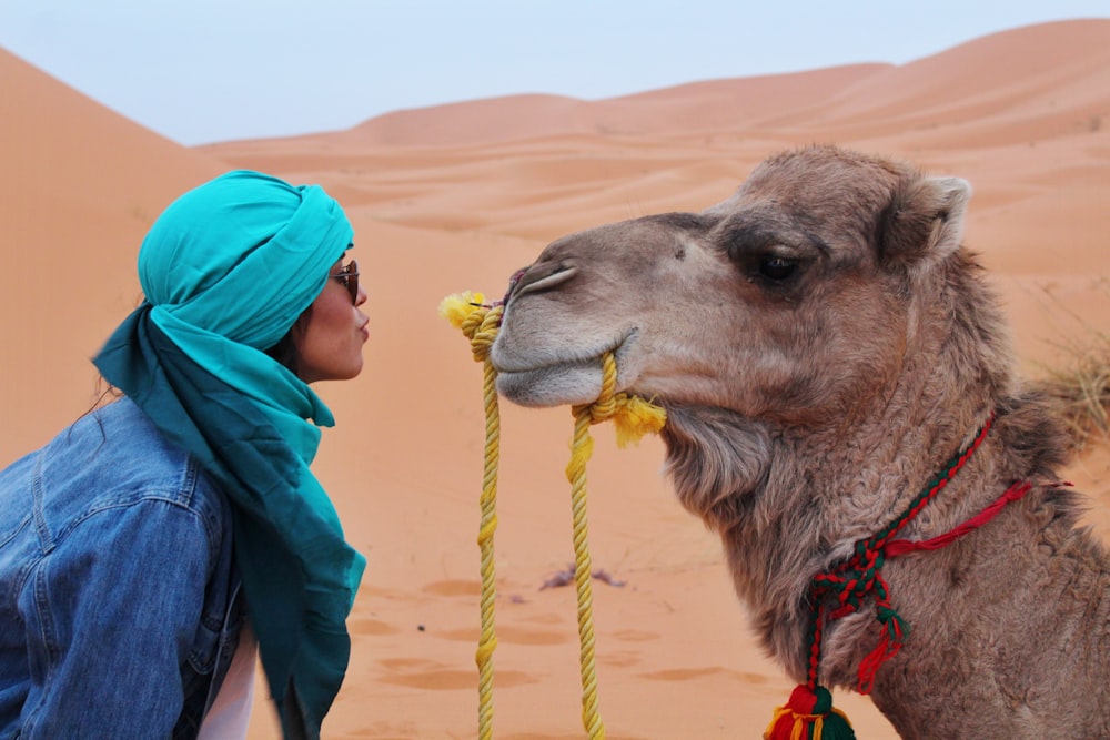 Mujer con chaqueta azul frente a camello marrón