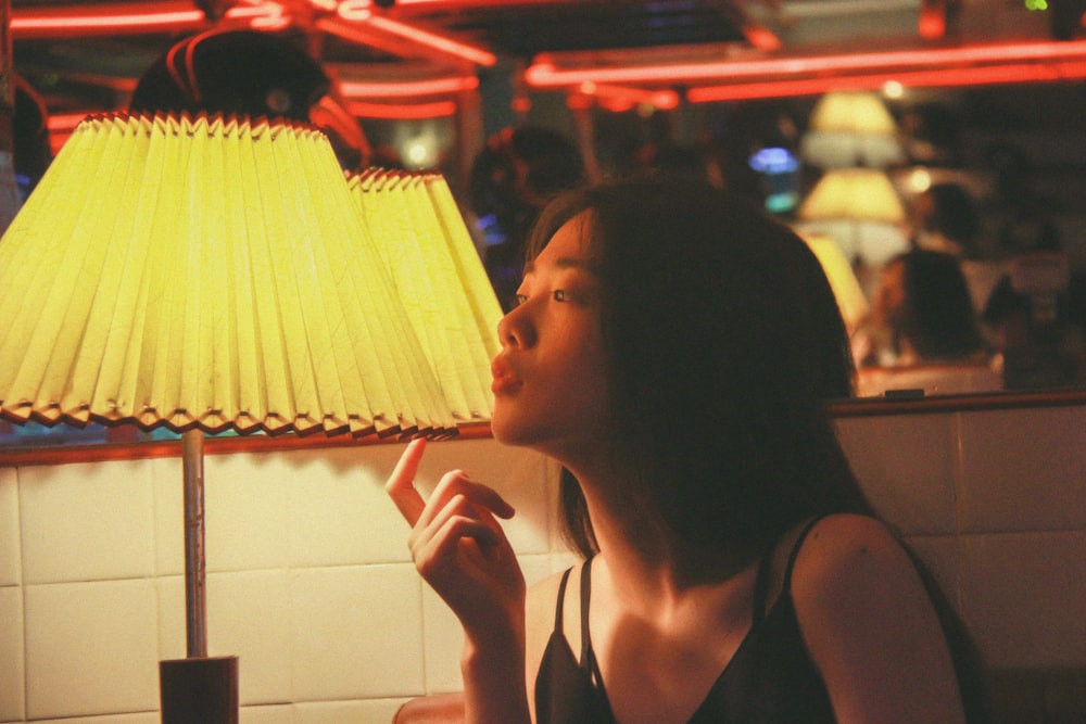 woman in black tank top sitting near table lamp