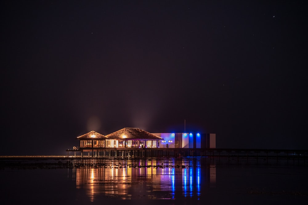 beleuchtetes Haus in der Nähe eines Gewässers während der Nacht