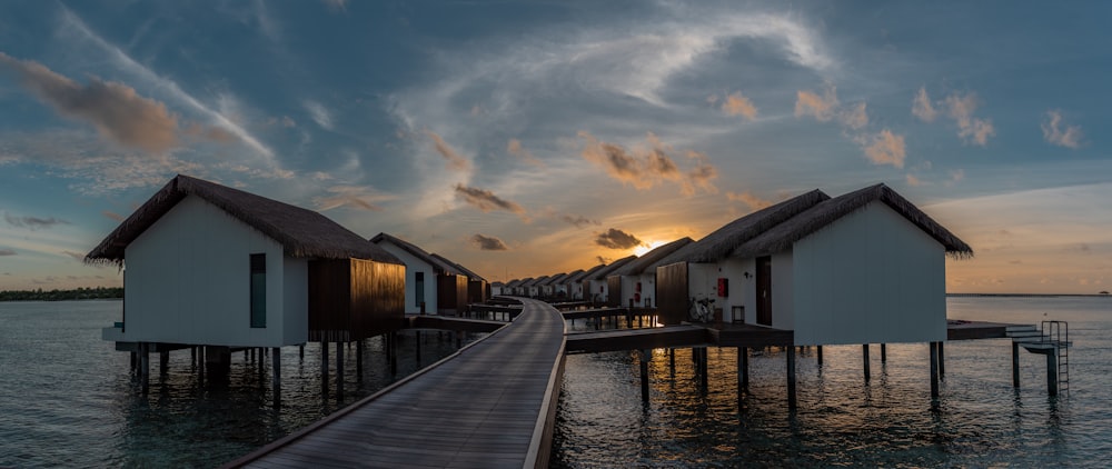 white and black wooden houses at beach during sunset