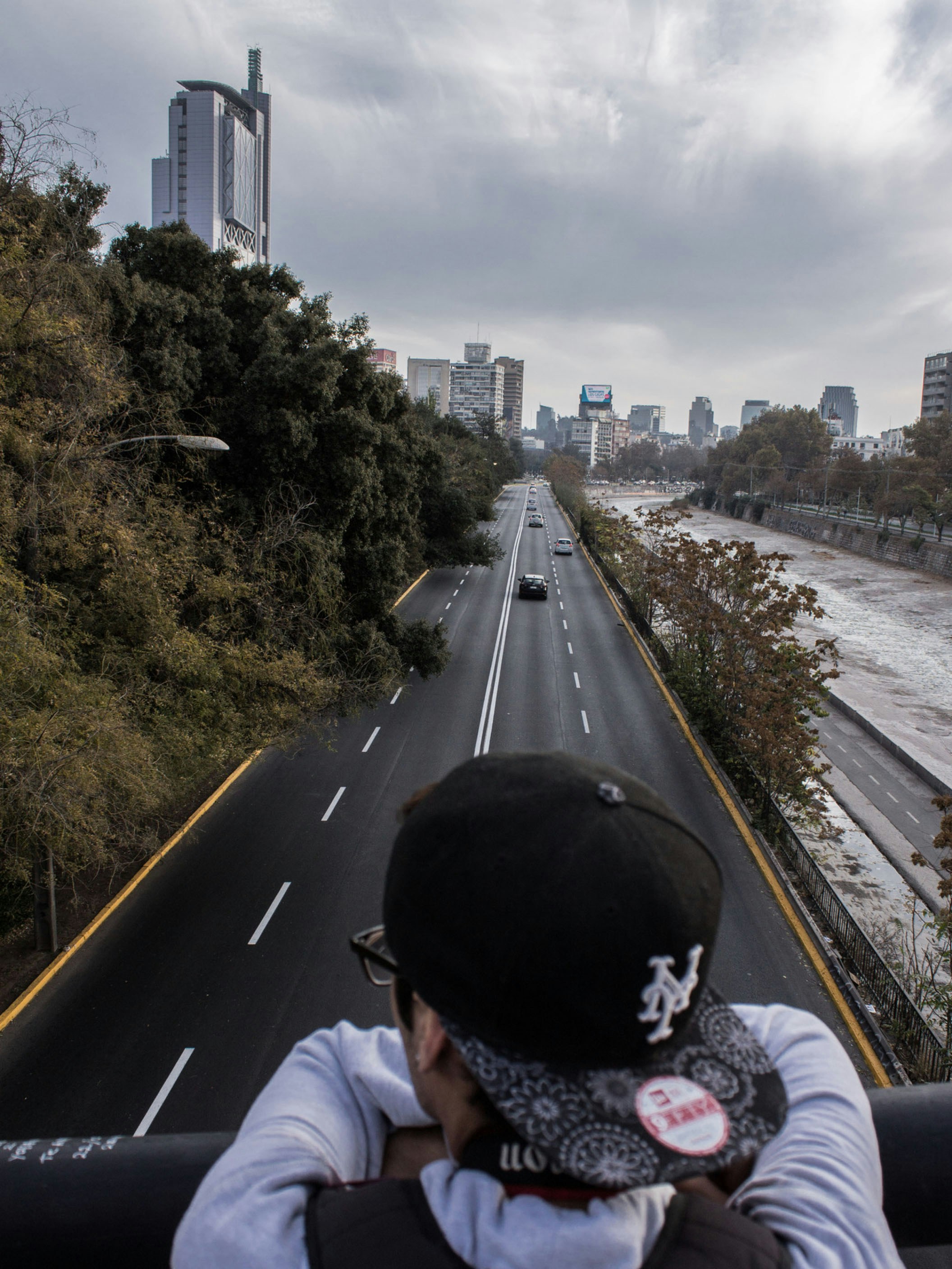 man leaning on metal rail above roads during daytime