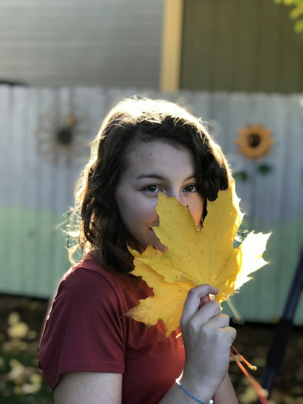 woman in red shirt smelling yellow maple leaf
