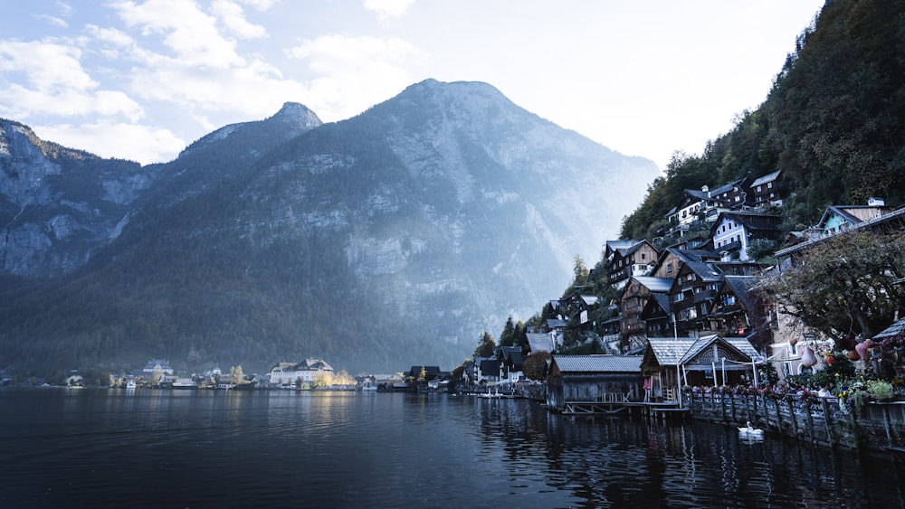 houses beside body of water near rocky mountain during daytime