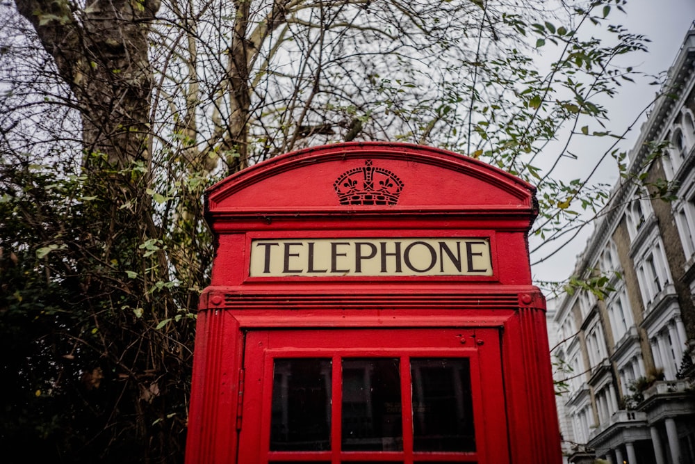 red telephone booth under green trees