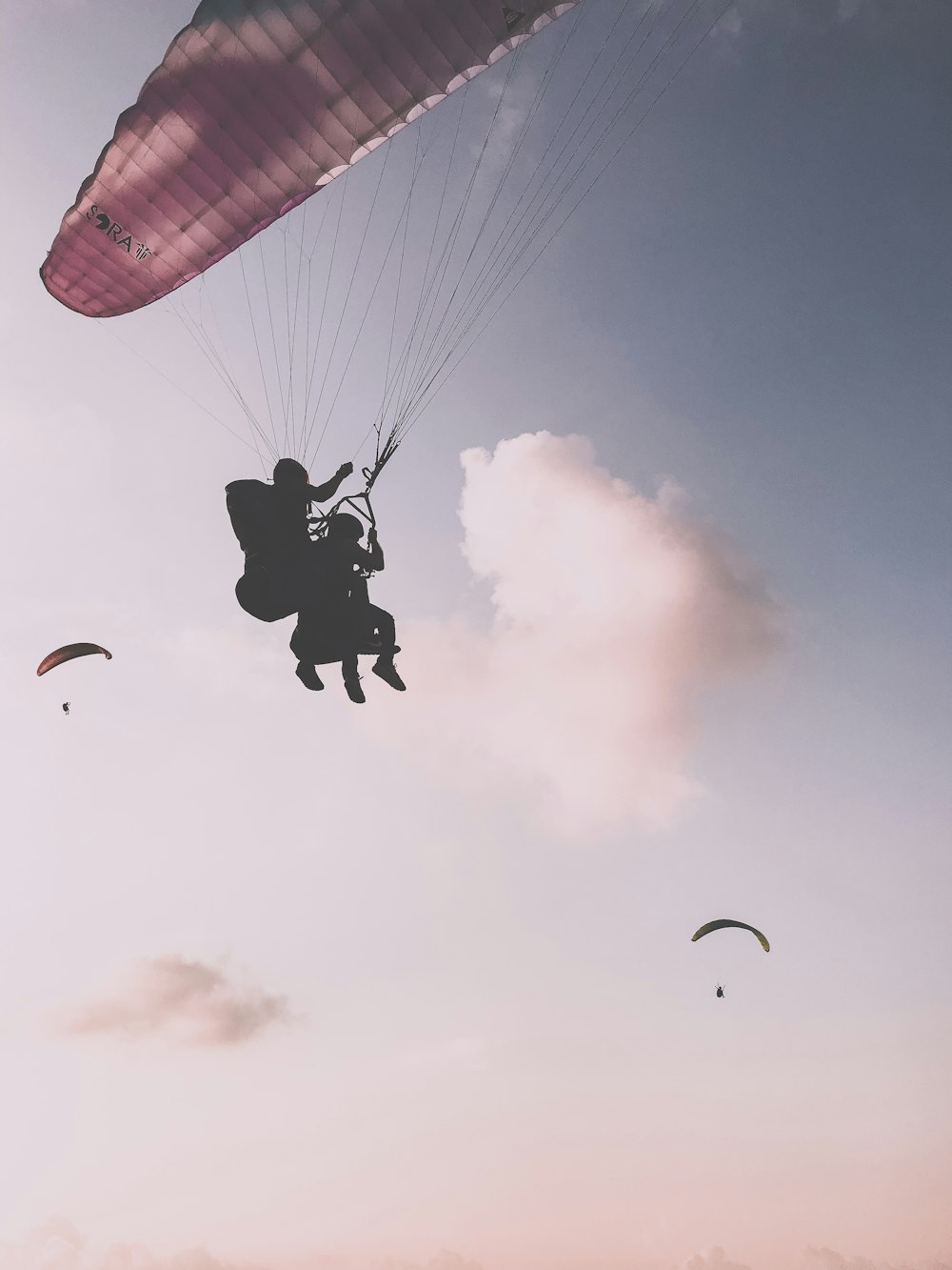 Silhouettenfotografie von zwei Personen beim Fallschirmspringen