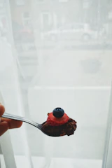 A smiling person enjoying a spoonful of gluten-free granola in a bright kitchen setting.