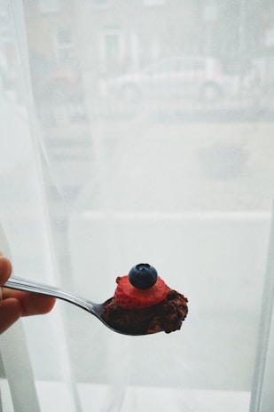 Close-up of a hand holding a spoonful of homemade granola with seeds and dried fruits.