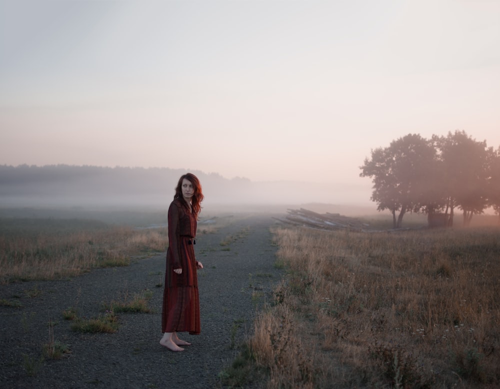 woman wearing brown dress standing on brown grass