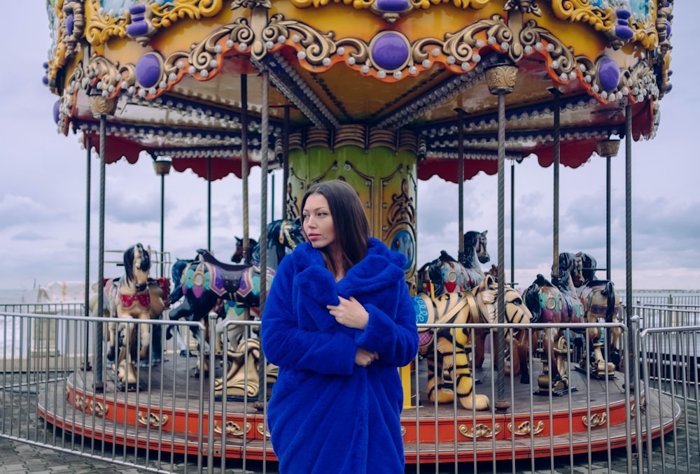 woman wearing blue coat near carousel