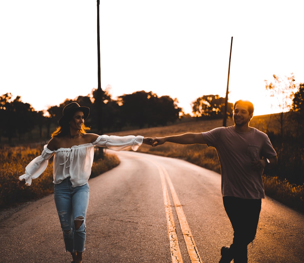 couple se tenant la main debout sur la route pendant le lever du soleil