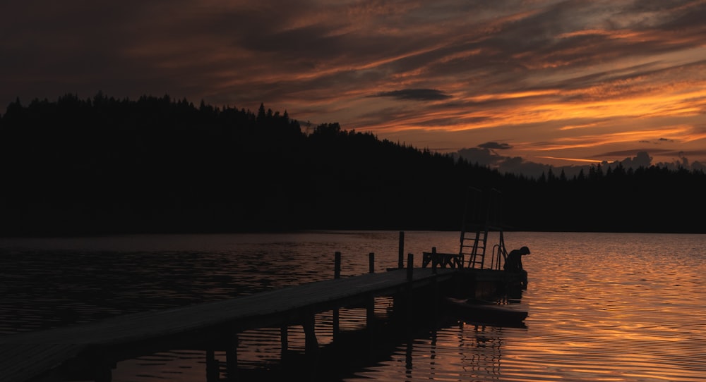 silhouette of dock under orange sky during golden hour